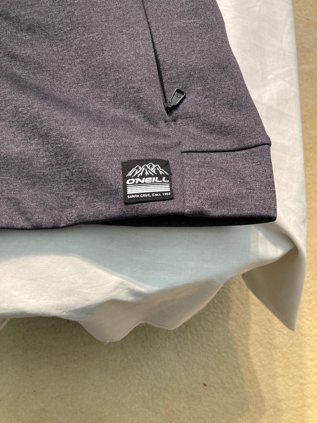 Gray zip-up hoodie with drawstrings and logo patch